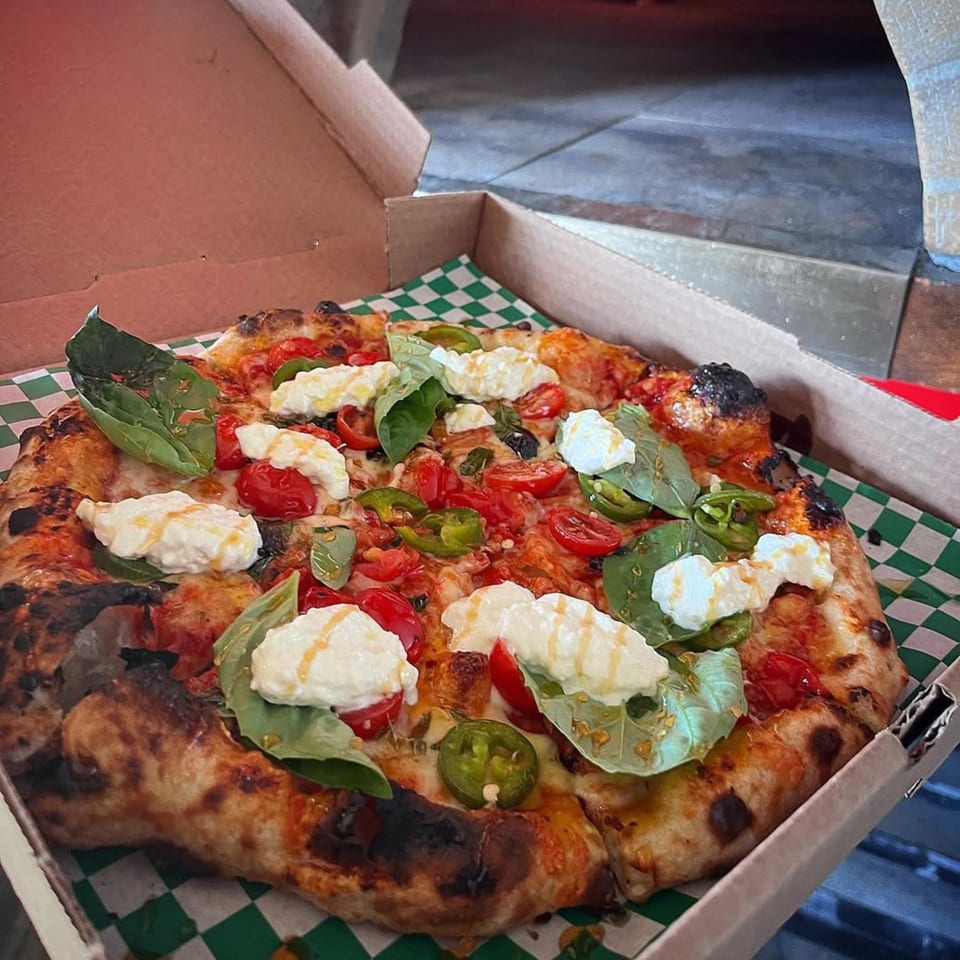 Coldpizza's pizza with fresh tomatoes, basil, jalapeños, and dollops of ricotta cheese in a box.